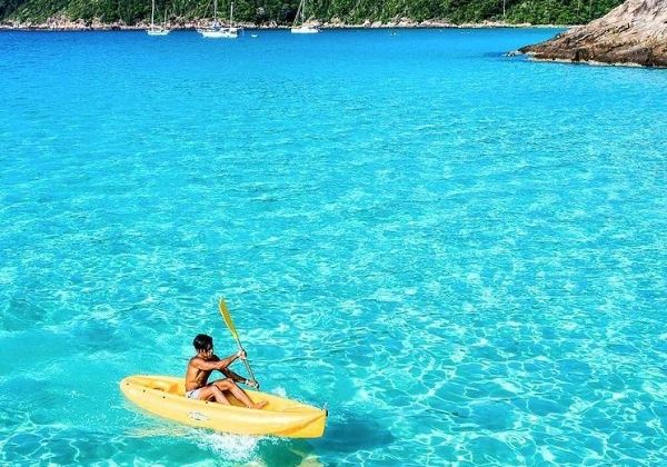 Kayaks moving across clear blue water