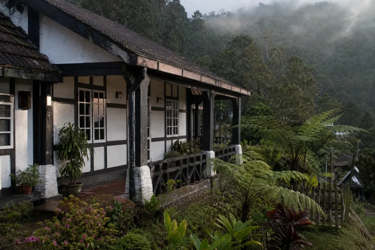 AI-created editorial interpretation of a weathered heritage bungalow and fern garden at Fraser's Hill after rain